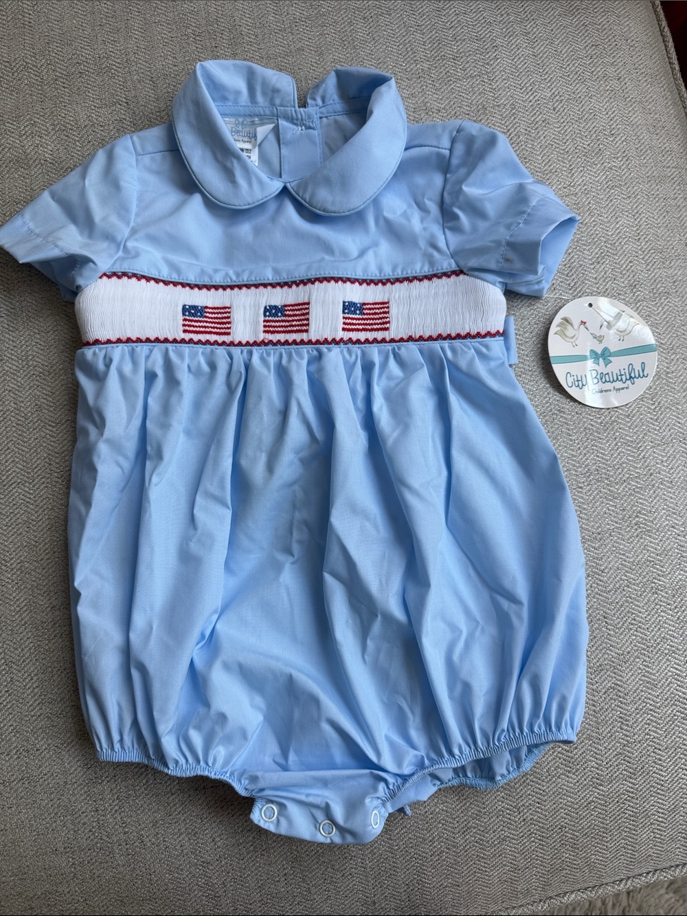 Light Blue Smocked Romper with Flag Embroidery. Size 2T
